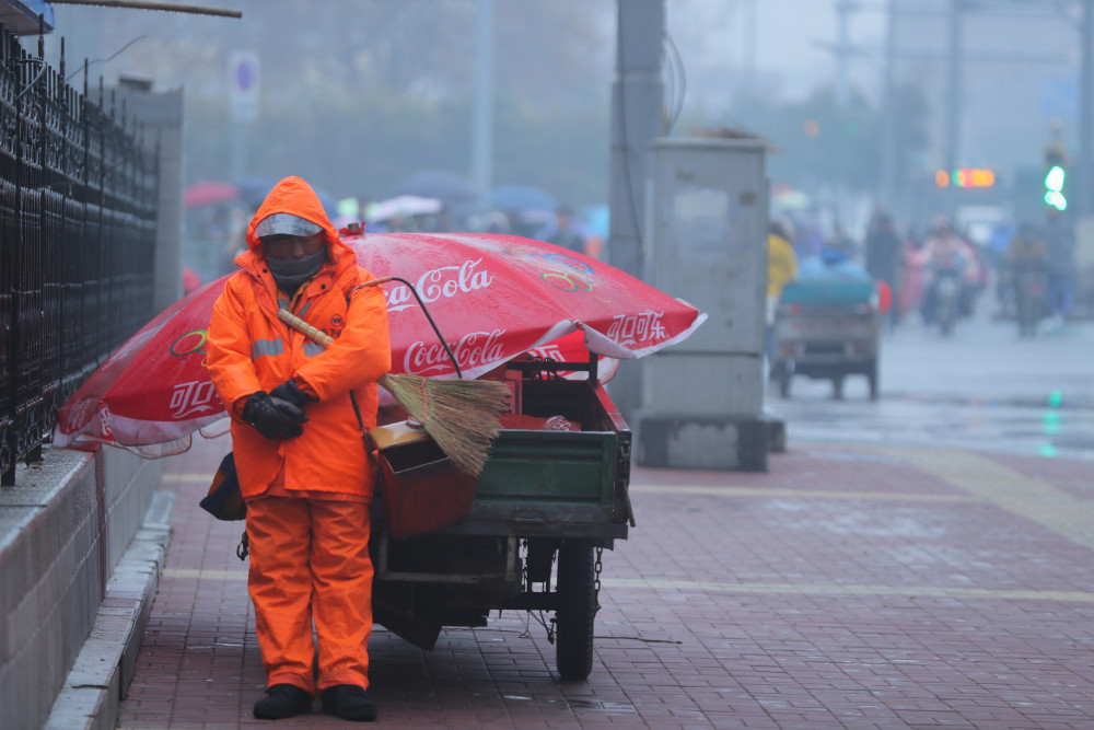 雨雪中坚守 环卫工怀抱扫把簸箕睡着了
